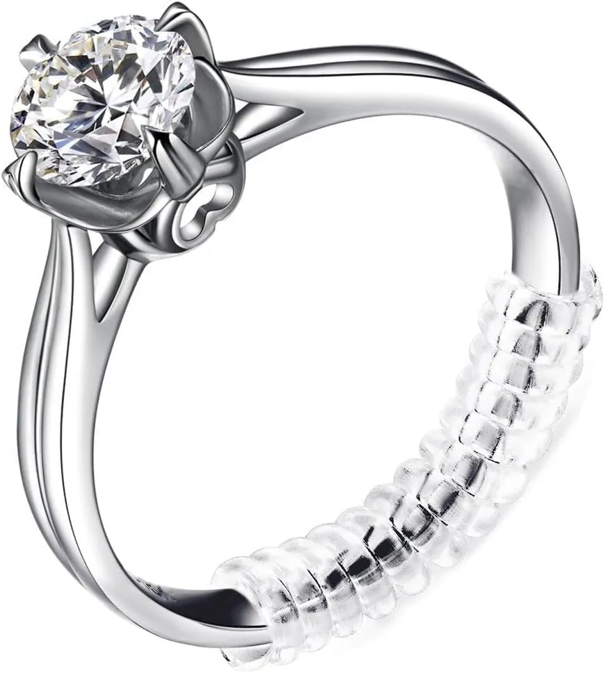 Detailed close-up of a silver solitaire ring featuring a prominent round brilliant-cut clear gemstone in a six-prong setting, with a transparent spiral ring size adjuster fitted on the band.